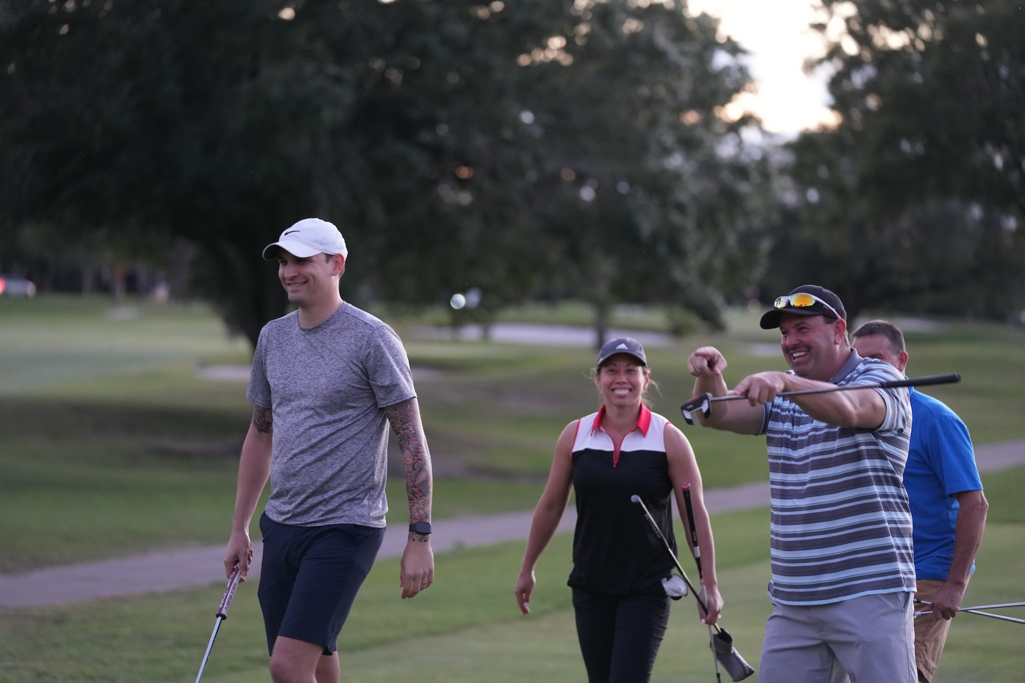 A group of league golfers walking the course at dusk